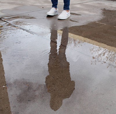 a students shadow in a puddle